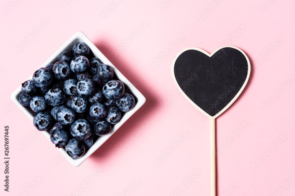 Fresh blueberries inside pot on pink background and heart. Fresh blueberries inside pot on pink background and heart.
