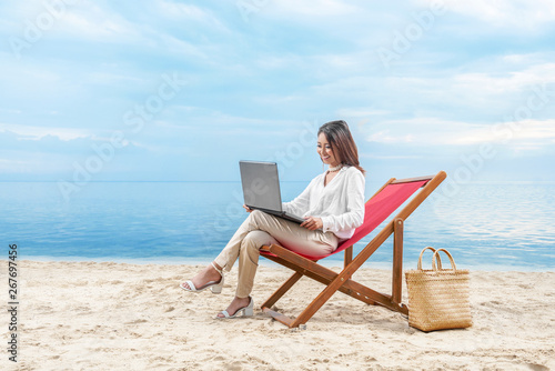 Asian business woman working with laptop sitting in the beach chair on beach © Leo Lintang