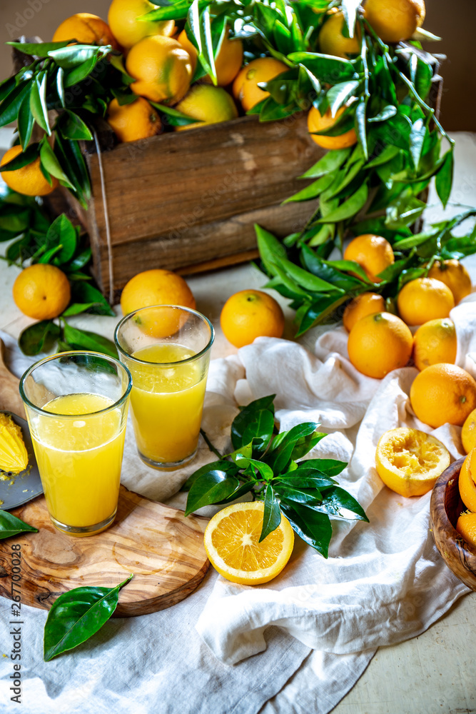 Table with box of fresh orange with orange tree branch and fresh orange juice Table with box of fresh orange with orange tree branch and fresh orange juice