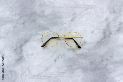 Stylish gold eyeglasses spectacles on marble background. Top view Copy space Minimal style