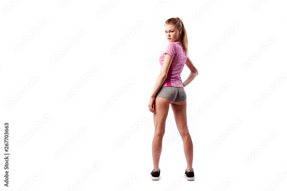 A young slim woman athlete in a sporty pink top and shorts posing and smilling on a white isolated background in studio. Portrait of a beautiful sportswoman A young slim woman athlete in a sporty pink top and shorts posing and smilling on a white isolated background in studio. Portrait of a beautiful sportswoman