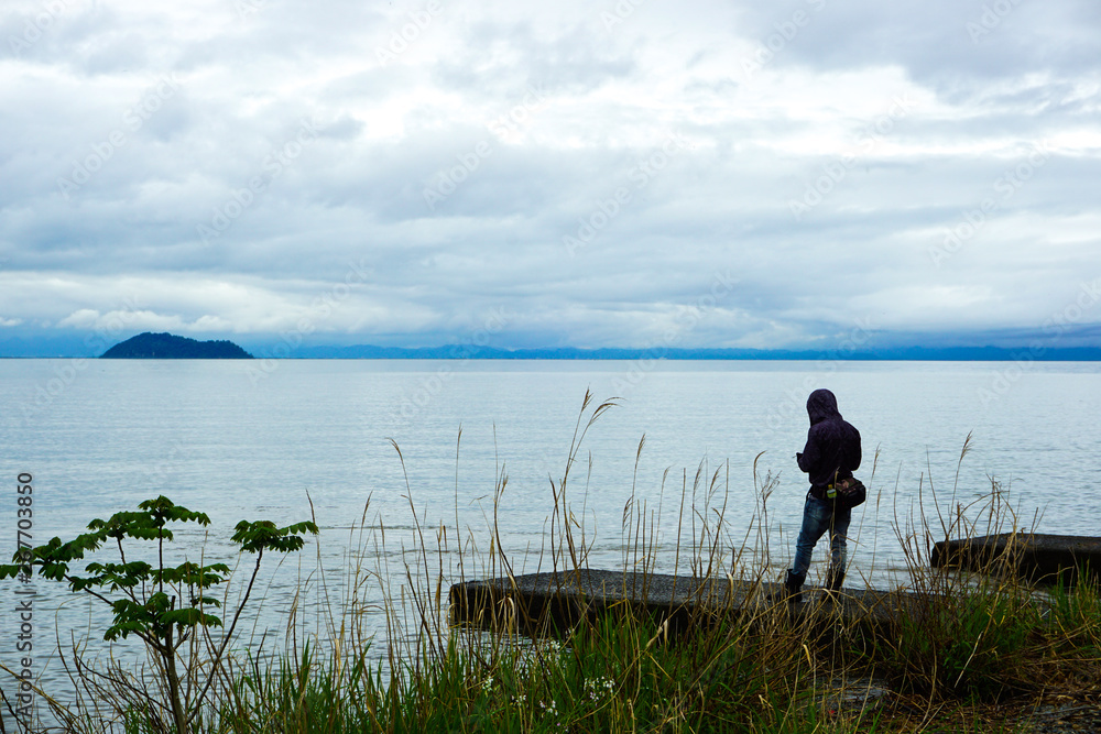 A man standing on the side of Lake Biwa.  びわ湖のサイドに立つ男