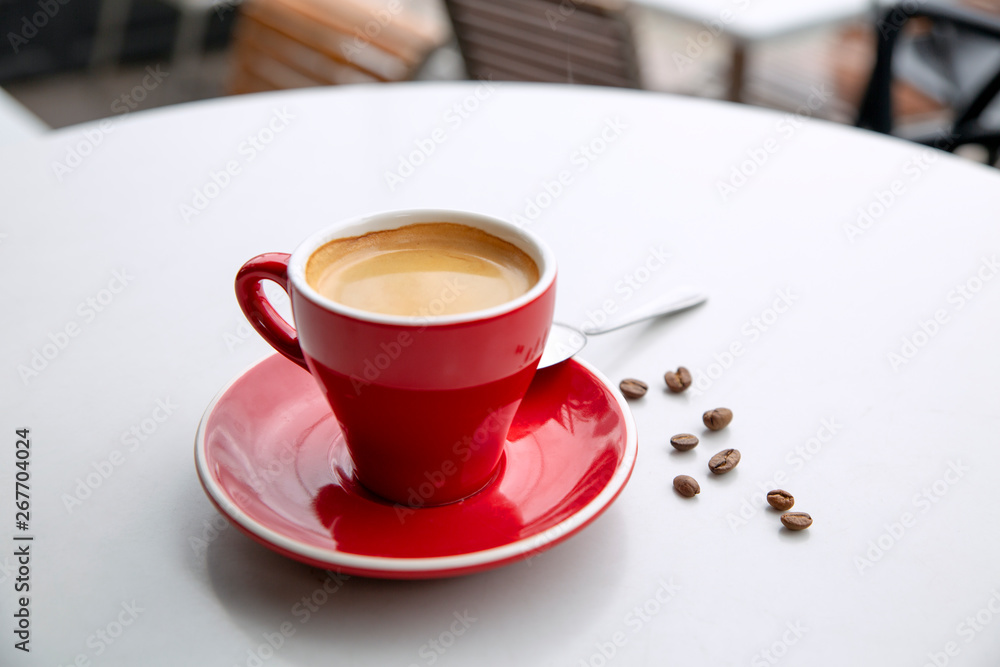 Obraz premium Red cappuccino coffee cup mug on a white cafe table interior with menu