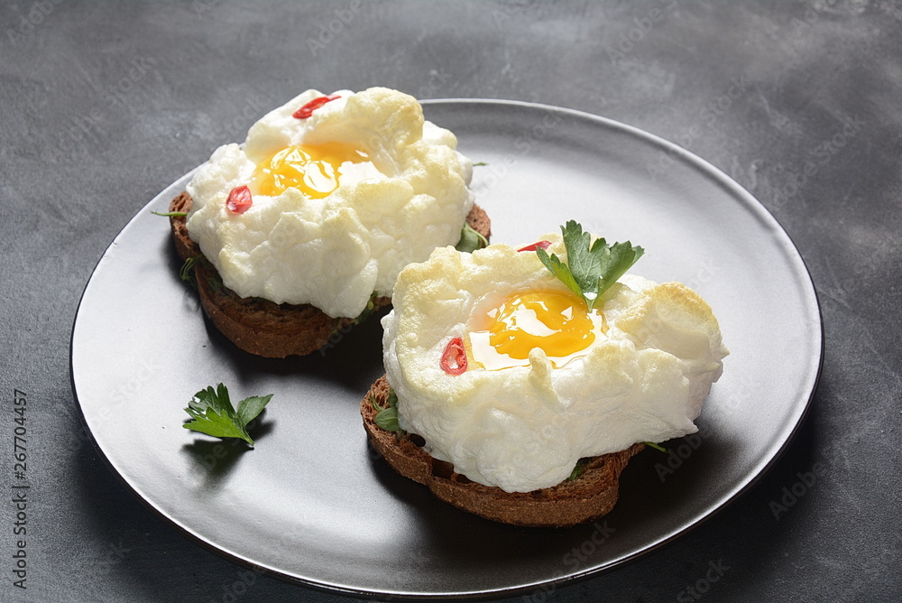 Delicate baked egg. Orsini eggs in the cloud. French breakfast.Cloud egg on toast Delicate baked egg. Orsini eggs in the cloud. French breakfast.Cloud egg on toast