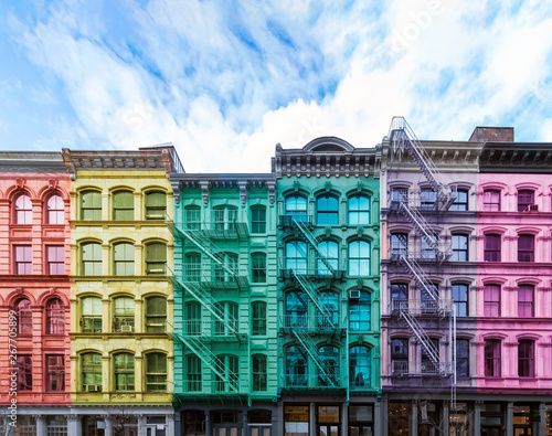 Rainbow colored block of old buildings in the SoHo neighborhood of Manhattan in New York City with blue sky background above photo