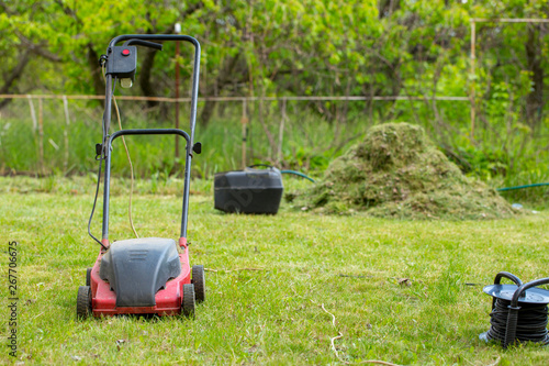 Electric lawn mower on the lawn on the background of mowed grass