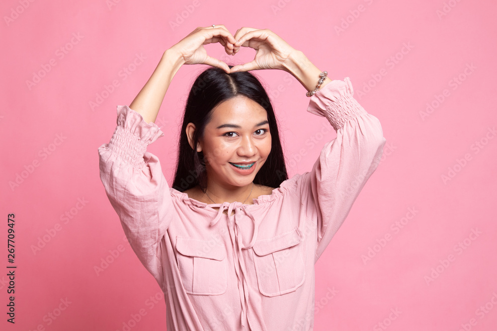 Young Asian woman gesturing heart hand sign. Young Asian woman gesturing heart hand sign.