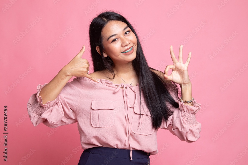 Young Asian woman show with phone gesture and OK sign. Young Asian woman show with phone gesture and OK sign.