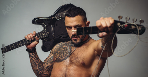 guitar player at rock concert. sexy abs of tattoo man hold broken electro guitar. sport and fitness. brutal sportsman torso. steroids. confidence charisma. muscular macho man with athletic body