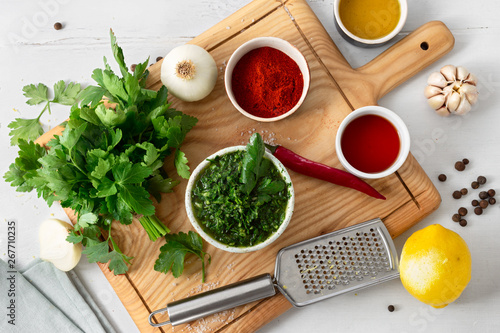 Cooking background. Raw ingredients for preparation Argentinian green Chimichurri or Chimmichurri salsa or sauce on white wooden table