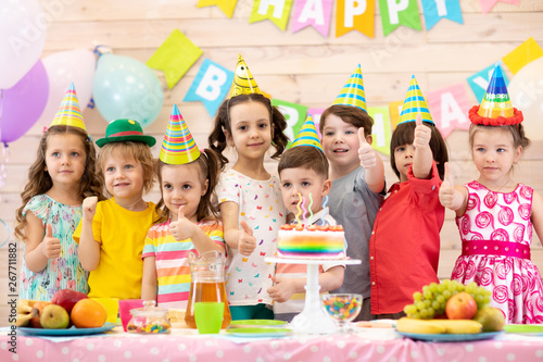 Group of preschool children having fun celebrating birthday party. Kids showing thumbs up sign or symbol