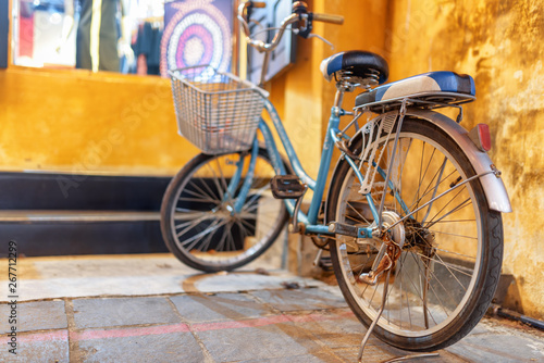 Blue vintage style bicycle parked at yellow wall, Hoi An