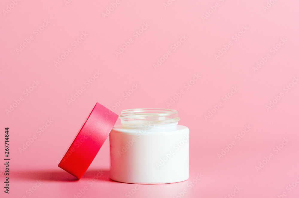 Face cream in white jar with a red cover on a pink background. Cosmetics, beauty. Minimal composition. Face cream in white jar with a red cover on a pink background. Cosmetics, beauty. Minimal composition.