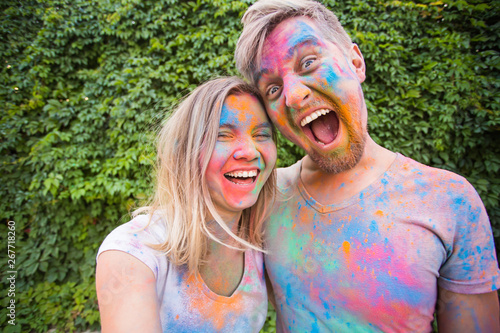Holiday  holi and people concept - Woman and man with painted faces taking selfie over bush backgrund