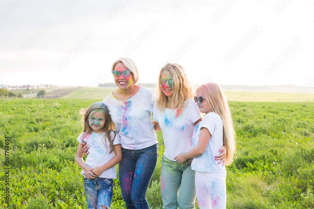 Friendship, Indian holidays and people concept - young women and children dancing on the summer field on festival of holi