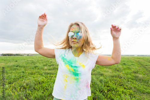 Fun  happy  people and holidays concept - Young cheerful woman at Holi paint party