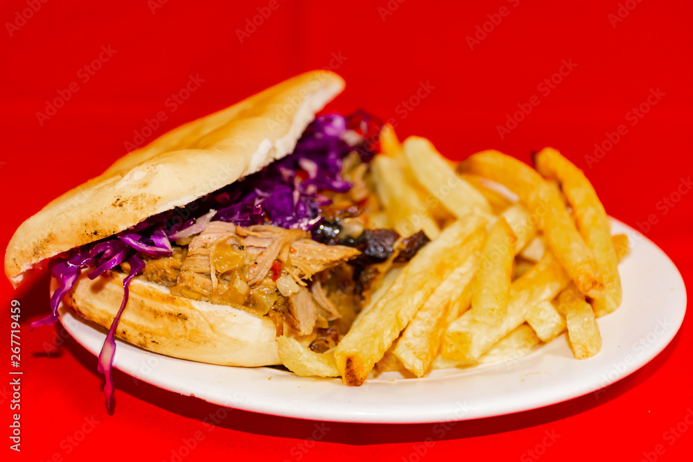 Pork cabbage sandwiches and fries. Plated with a red background.