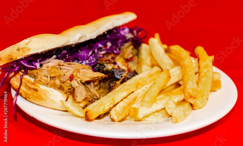 Pork cabbage sandwiches and fries. Plated with a red background.