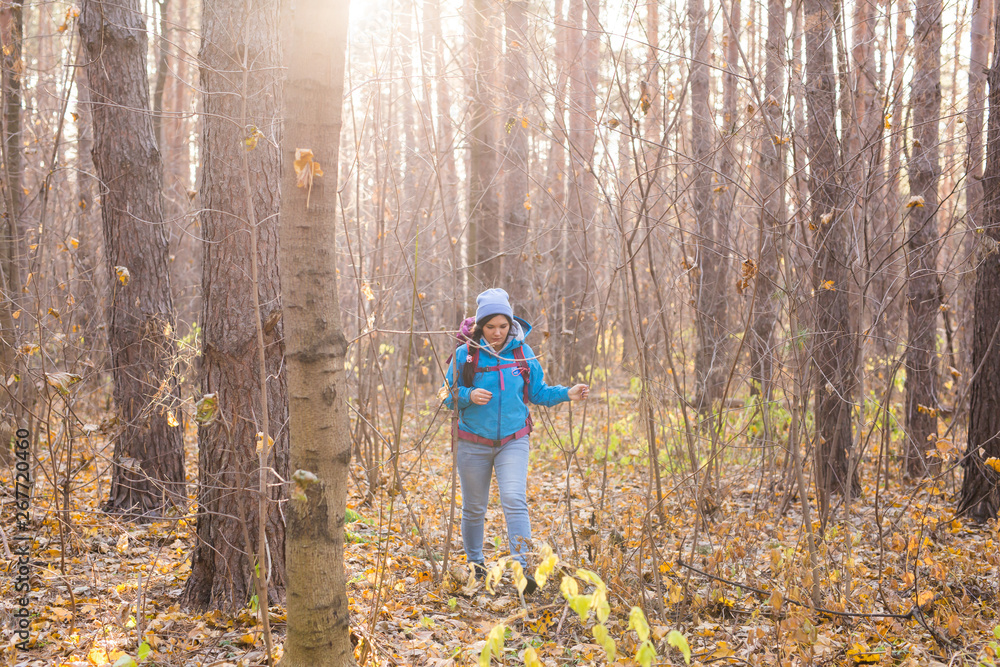 adventure, travel, tourism, hike and people concept - smiling tourist woman walking with backpacks over autumn natural background adventure, travel, tourism, hike and people concept - smiling tourist woman walking with backpacks over autumn natural background