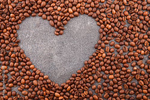 Roasted coffee beans on a grey table Grains of coffee in the shape of a heart on a gray background.