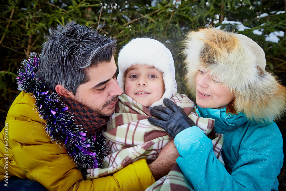 Obraz premium Happy family walking in a winter forest. New Year and Christmas concept