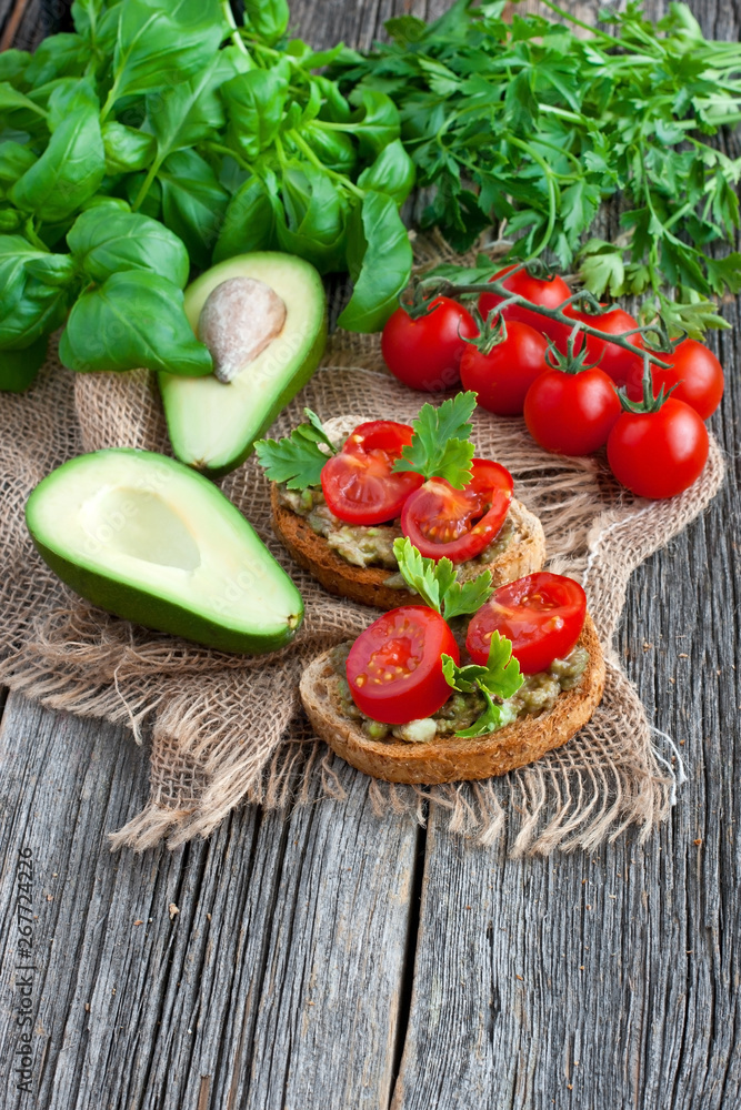 Fresh tomatoes and avocado pieces on wooden background