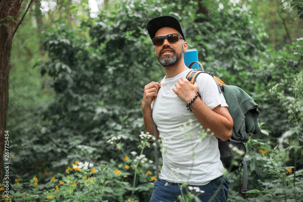 A young guy with a backpack in the cap, traveller in the woods, Hiking, Forest, Journey A young guy with a backpack in the cap, traveller in the woods, Hiking, Forest, Journey