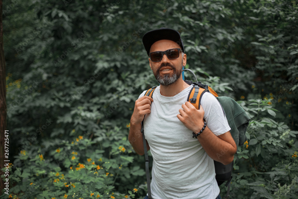 A young guy with a backpack in the cap, traveller in the woods, Hiking, Forest, Journey A young guy with a backpack in the cap, traveller in the woods, Hiking, Forest, Journey