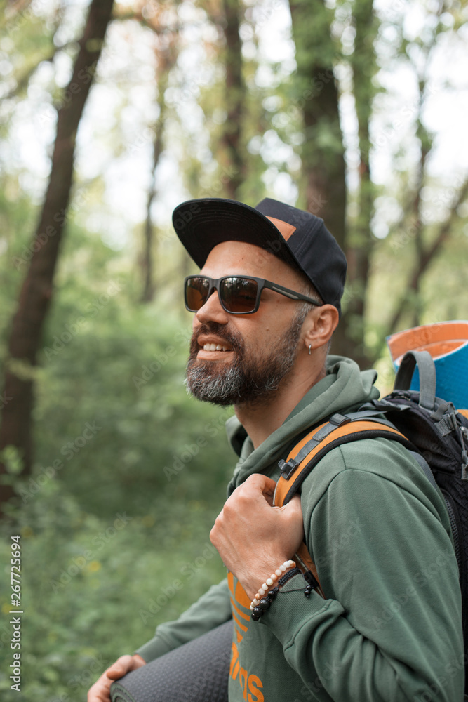 A young guy with a backpack in the cap, traveller in the woods, Hiking, Forest, Journey A young guy with a backpack in the cap, traveller in the woods, Hiking, Forest, Journey