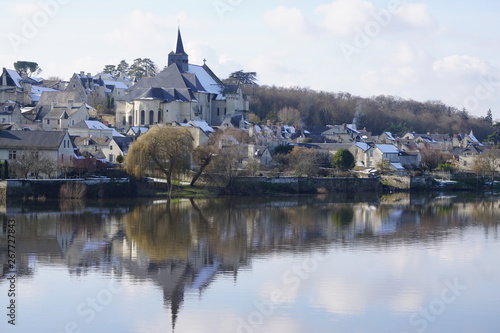 mirror reflection of an old stone church and village on a white winter day in the Loire Valley, France