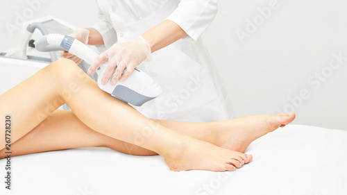 Laser ipl device in doctor hand. Woman body hair removal. Perfect epilator. Cosmetology leg technology photo