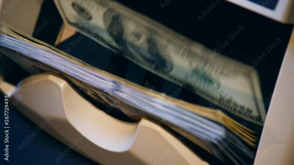 Banking equipment counts printed dollar bills. Banking equipment counts printed dollar bills.