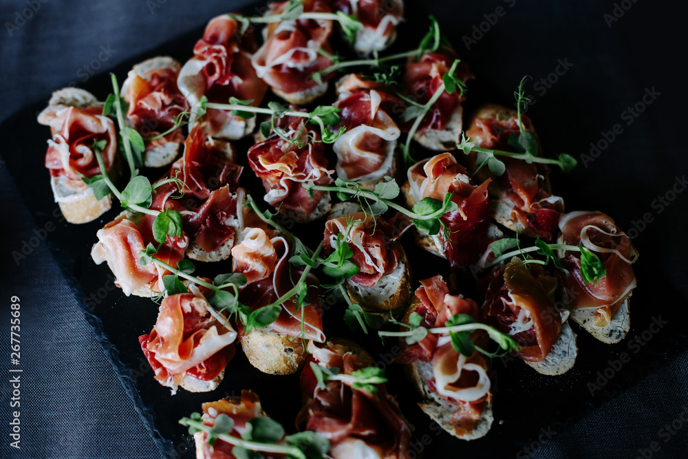Canapes with prosciutto and green pea leaves.