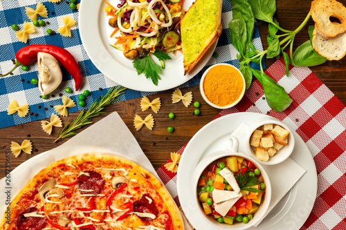 Top view image of italian style business lunch of pizza, soup and salad at wooden table background. photo