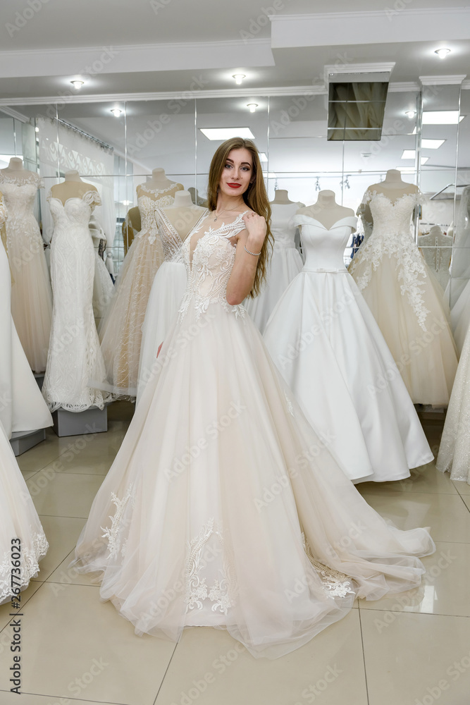 Attractive young woman wearing wedding dress in bridal shop Attractive young woman wearing wedding dress in bridal shop
