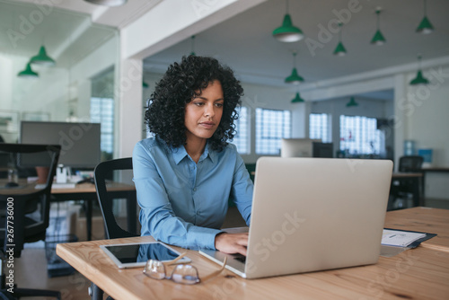 Focused young businesswoman using a laptop at her office desk