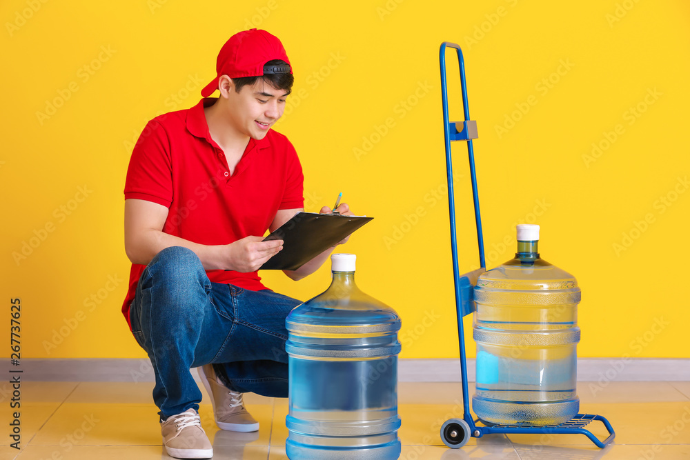 Asian delivery courier with bottles of water and clipboard indoors Asian delivery courier with bottles of water and clipboard indoors
