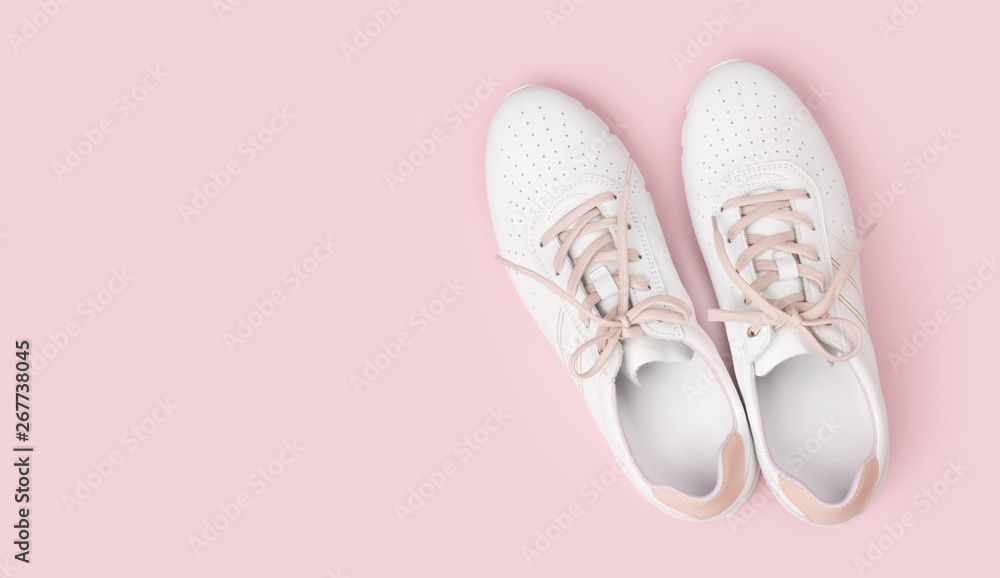 White leather sneakers with laces isolated on pink background