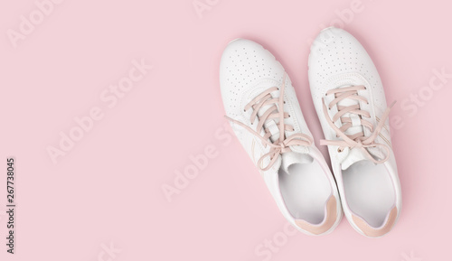 White leather sneakers with laces isolated on pink background