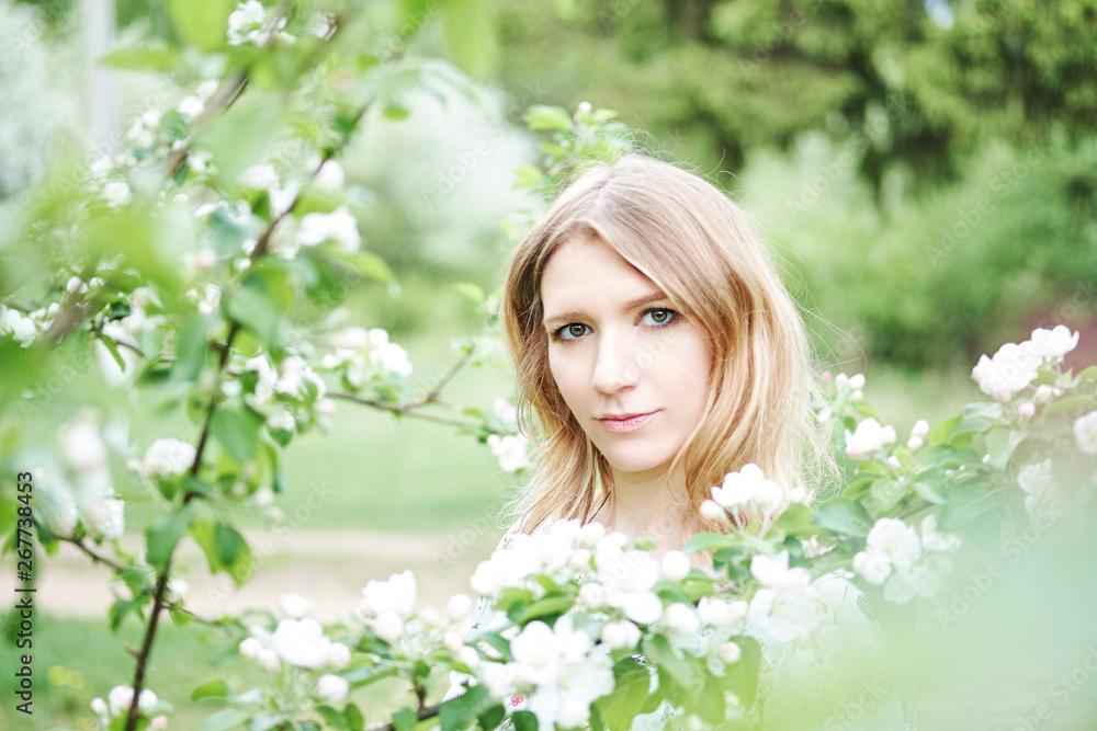 beautiful, pregnant girl in a green dress is standing in a flowered garden beautiful, pregnant girl in a green dress is standing in a flowered garden