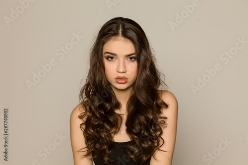 Young woman with makeup and long hair, posing on white background