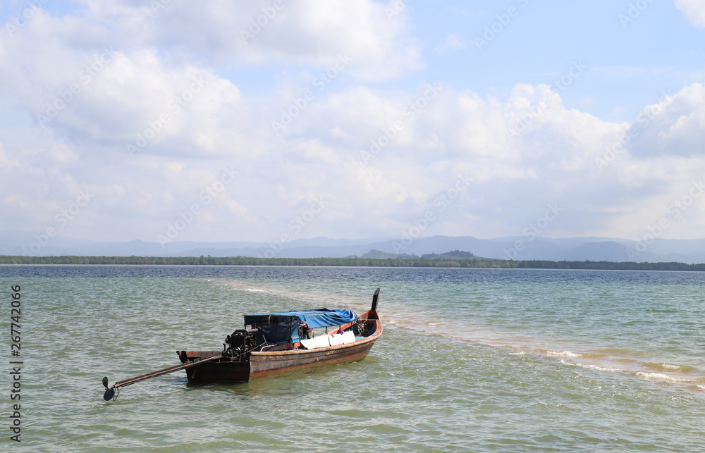 Scenery of local fishery boat, adapted to be touristic boat lie at anchor in Andaman with cloudy blue sky background. sea.