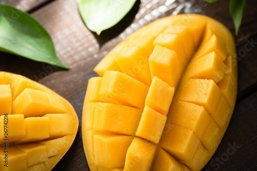 Fresh ripe mango fruit cut into cubes on wooden table background. Closeup view. Healthy vegetarian tropical fruit