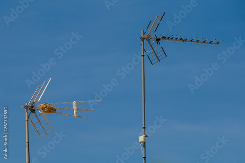 television antenna on a rooftop in front of a blue sky © StudioLaMagica