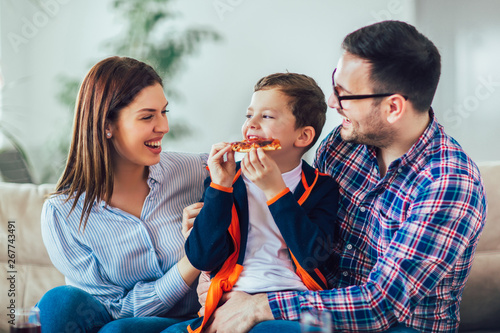 Portrait of happy family eating pizza while sitting on sofa at home