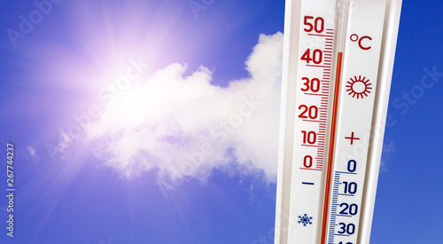 The thermometer on the background of the sky with a bright sun shows 45 degrees of heat