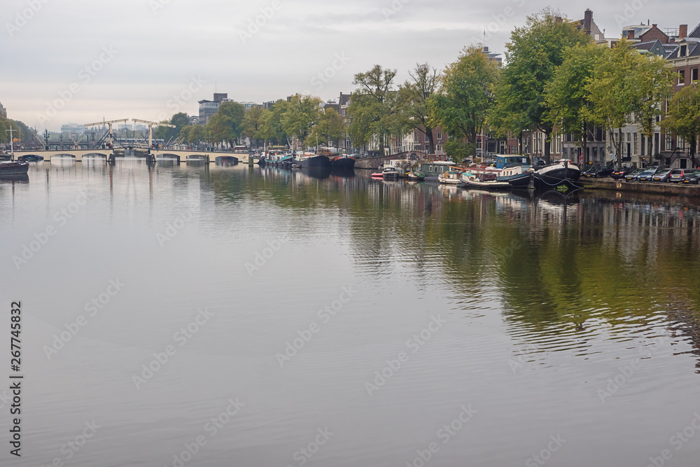 The Skinny Bridge spanning the river with boats on both banks of the Amstel