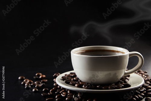 A cu[ of coffee and coffe beans on black background.