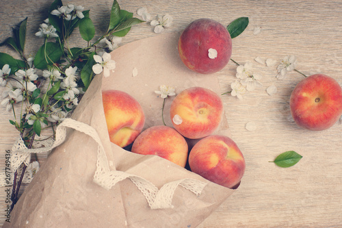 Ripe peaches are poured out of a package made from craft paper, top view