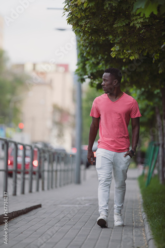 African american man in living coral t-shirt walking at city street, casual style